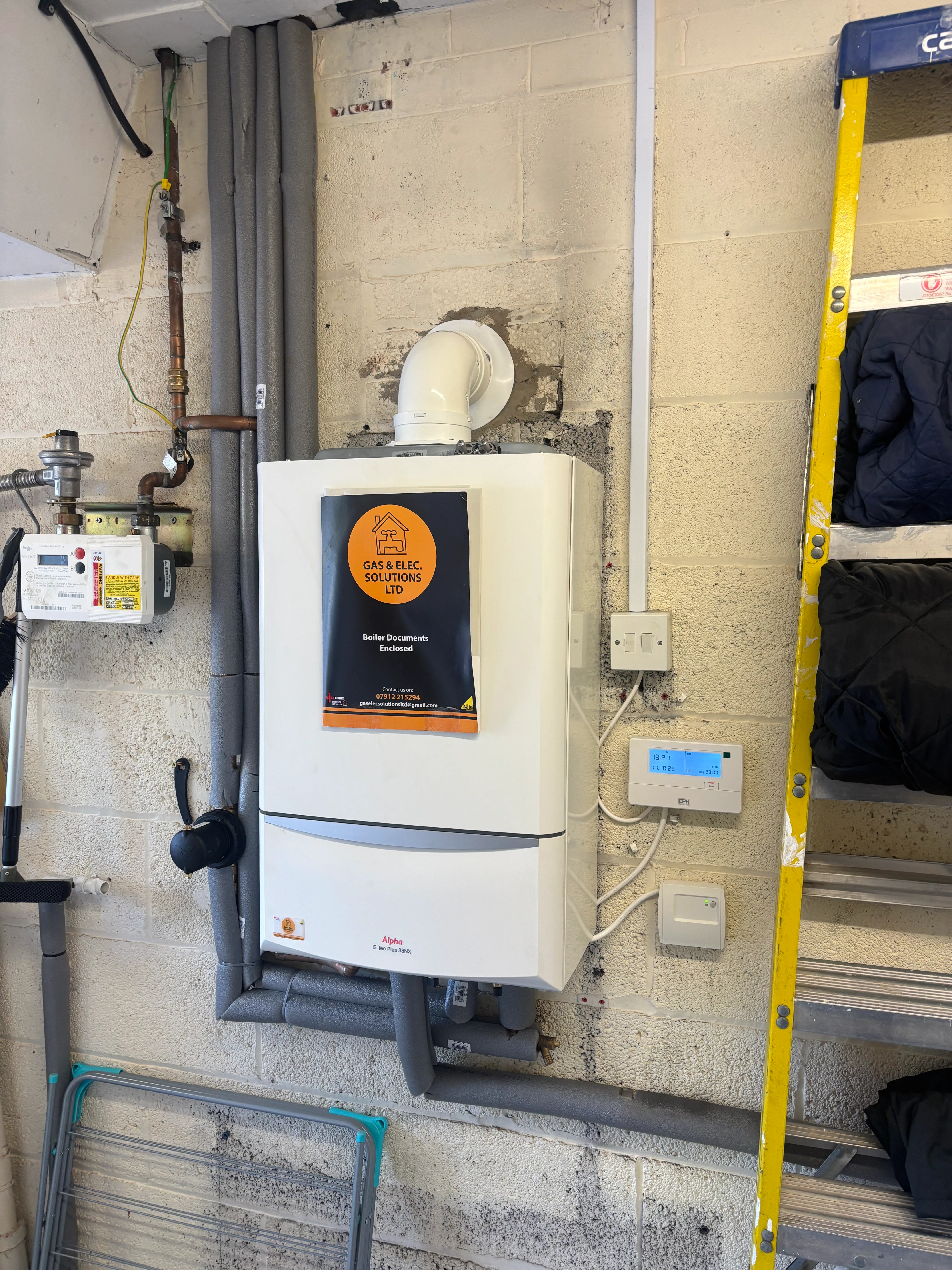 A water heater sitting on a wall next to a ladder.